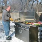 Man cooking food on a bbq in the snow