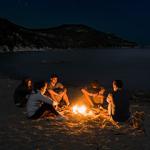 People sat around a campfire on the beach