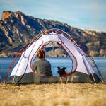 Woman in tent with her dog in front of a lake