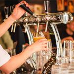 Person pulling a pint at a bar