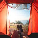 Person laying with their feet out of a tent doorway