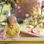 Child climbing out of a sandpit in a garden on a sunny day