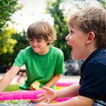 Two boys having a water fight in a garden