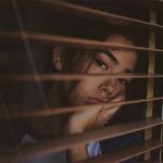 A woman looking bored whilst looking out of a window