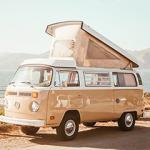 A cream volkswagen campervan with a pop-top roof