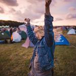 A woman dancing amongst tents at a festival