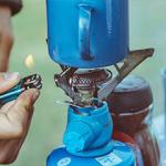 A person lighting a gas camping stove